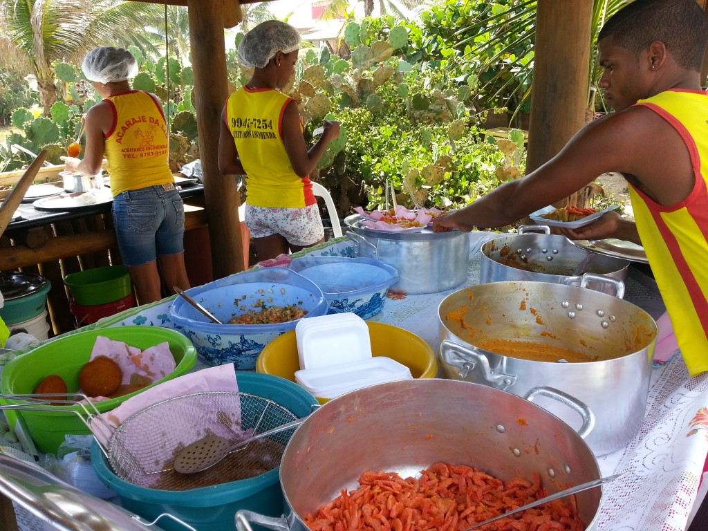 Na bacia verde, acarajé. Na panela da direita, parte de baixo, camarão. E logo acima do camarão, panela com vatapá